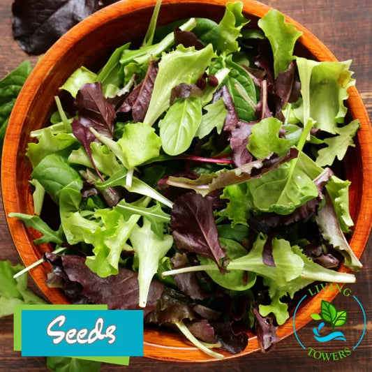 Wooden bowl filled with mixed green leafy vegetables on a wooden surface, with 'Seeds' brand logo visible.