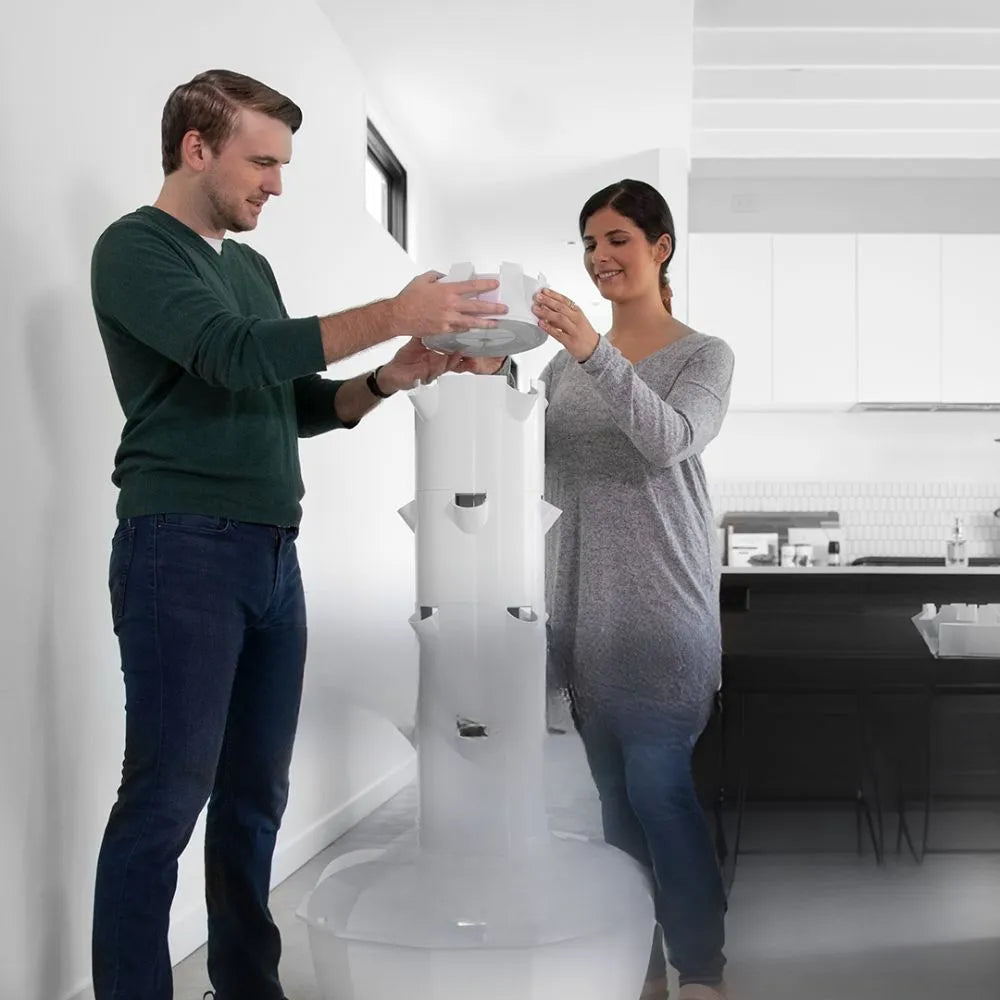 Two people assembling a Tower Garden inside a home